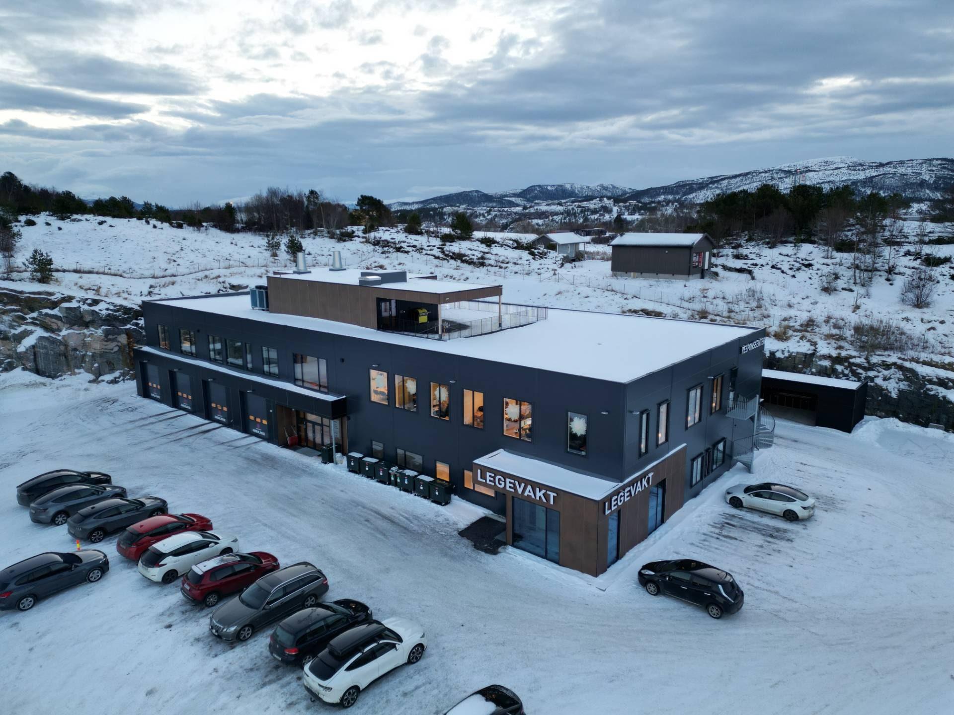 Blålysbygget sett fra lufta, med snø rundt og biler på parkeringsplassen